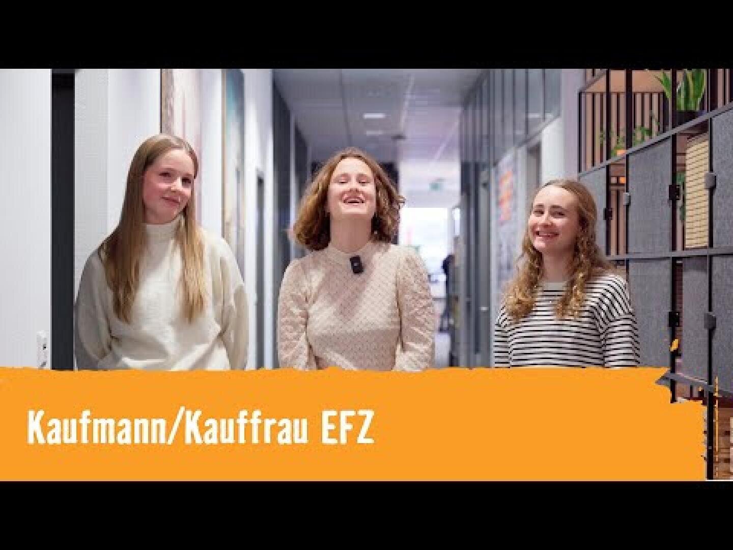 Drei junge Frauen stehen lächelnd in einem Büroflur. Unten ist in weißer Schrift auf orangefarbenem Hintergrund der Text „Kaufmann/Kauffrau EFZ“ zu lesen. Auf der rechten Seite ist eine moderne Büroeinrichtung zu sehen.