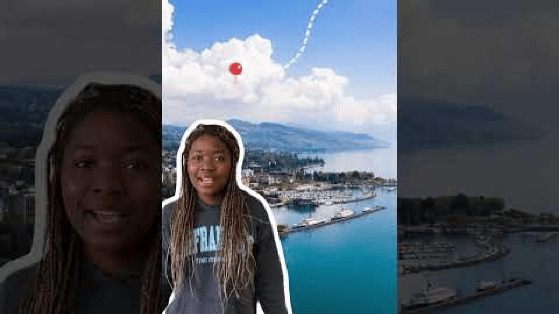 Eine Frau mit langen geflochtenen Haaren und einem dunklen Sweatshirt steht vor einem bearbeiteten Hintergrund, der eine Küstenstadt, Berge, Wasser und einen Himmel mit einer gepunkteten Linie zeigt, die zu einem roten Punkt in den Wolken führt.