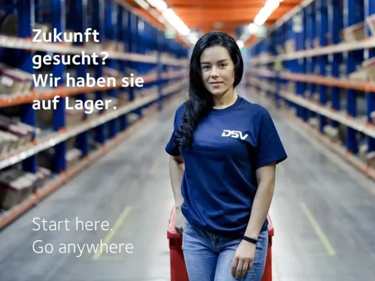 Eine Frau steht selbstbewusst mit verschränkten Armen in einem Lagerhaus und trägt ein marineblaues DSV-Shirt. Der deutsche Text lautet: „Zukunft gesucht? Wir haben sie auf Lager.“ Der englische Text: „Start here. Go anywhere.“.