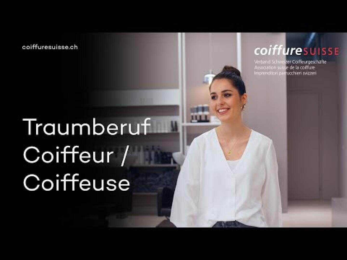Eine Frau mit nach hinten gebundenen dunklen Haaren, die eine weiße Bluse trägt, steht lächelnd in einem modernen Friseursalon. Auf dem Bild ist der Text „Traumberuf Coiffeur / Coiffeuse“ zu lesen, zusammen mit den Logos von coiffuresuisse.ch und Coiffure Suisse.